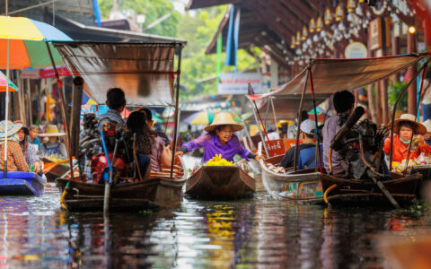 Women market trader sells fruit to tourists while touring around the Floating Market at Damnoen Saduak, Thailand
